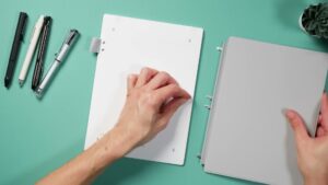 Supernote Manta mit weißer Rückseite neben dem abgenommenen grauen Half Folio und dessen Haken.