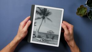 Kindle Scribe von 2024 mit weißem Innenrahmen und dunkler seitlicher Grifffläche in zwei Händen.