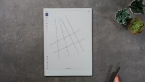 Paper Pro mit mehreren langen Testlinien auf einer Notizseite; der Stift liegt am unteren Bildrand in der Hand.