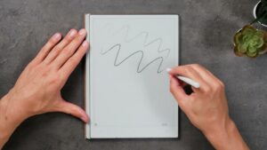 Hand zeichnet helle und dunkle Wellenlinien mit dem weißen Stift auf dem AiPaper.