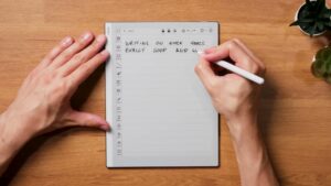 Hand schreibt mit dem weißen Stift auf einer linierten Notizseite des Go 10.3.