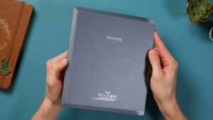Rückseite des grauen Penstar eNote in beiden Händen, mit Penstar-Schriftzug und schmal zulaufenden Rändern.