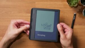 Schwarzer Kobo Libra Colour in der Hand, mit zwei Tasten an der linken Griffseite.