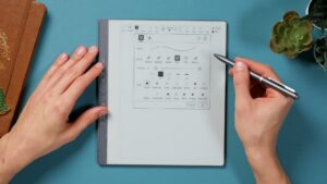Penstar eNote mit geöffnetem Stiftmenü; der graue Stift wird rechts neben der Anzeige gehalten.