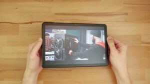 NXTPAPER 10s im Querformat in beiden Händen, mit farbigem Inhalt und diffuser Aufhellung auf dem Display.